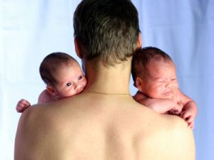 Twin babies looking over fathers shoulder